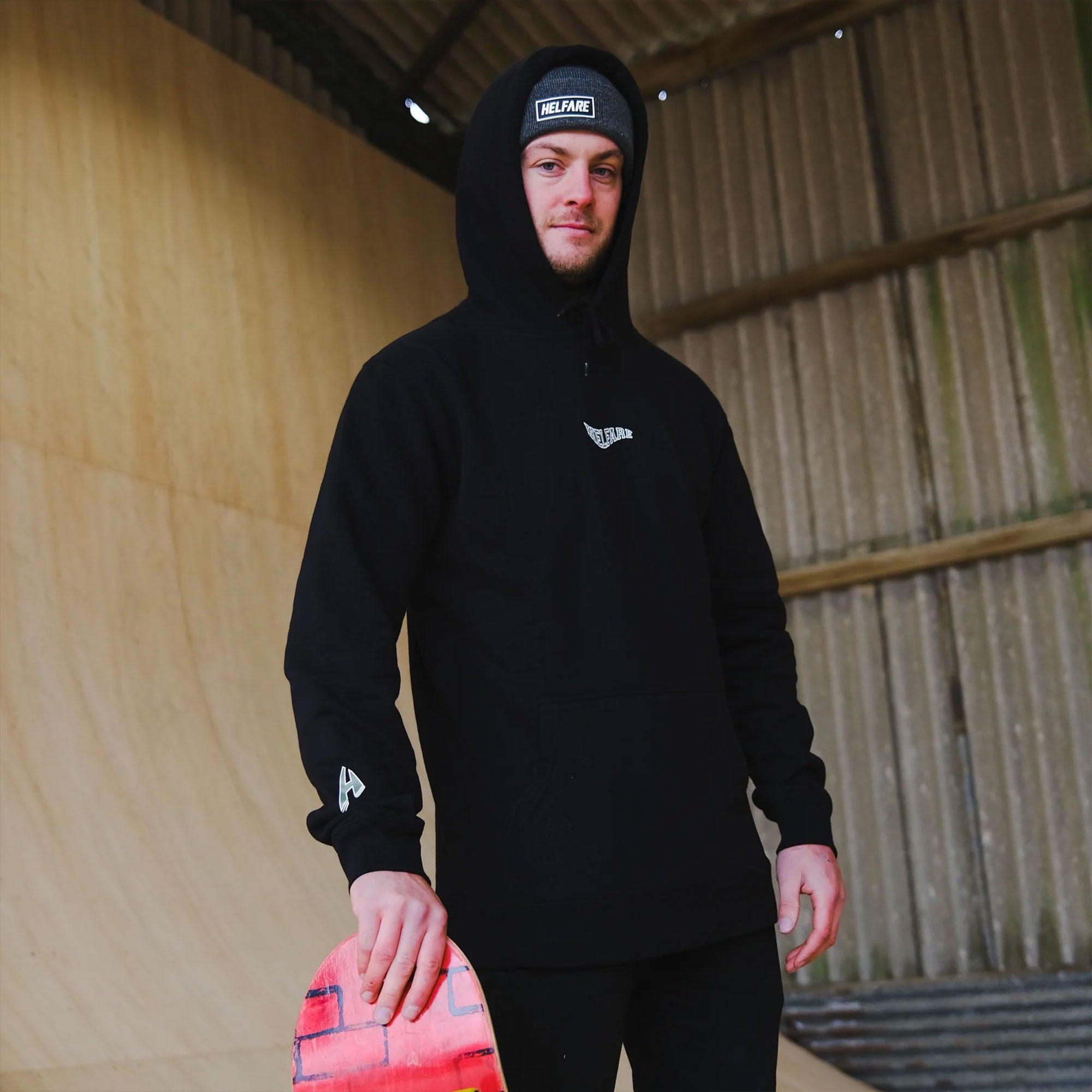 HELFARE Varsity Hoodie I Black | Pose with hood up